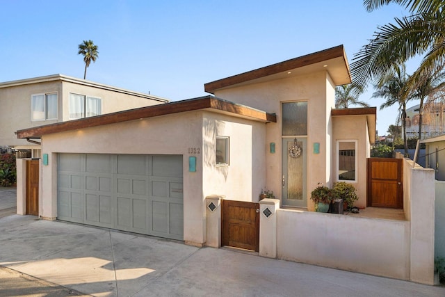 view of front of house featuring driveway, a garage, fence, and stucco siding