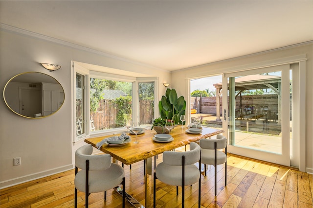 dining space featuring light wood-style floors, crown molding, and baseboards