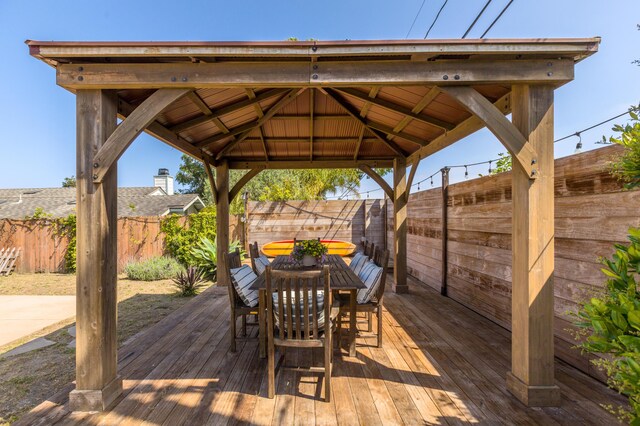 wooden terrace featuring a fenced backyard, a gazebo, and outdoor dining space