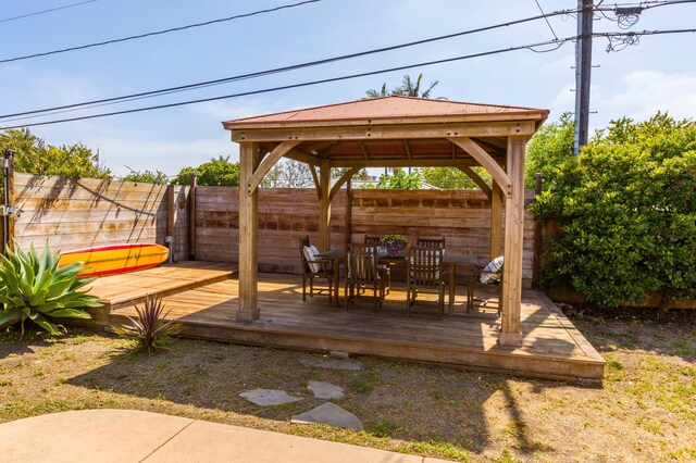 wooden terrace with a fenced backyard, a gazebo, and outdoor dining area