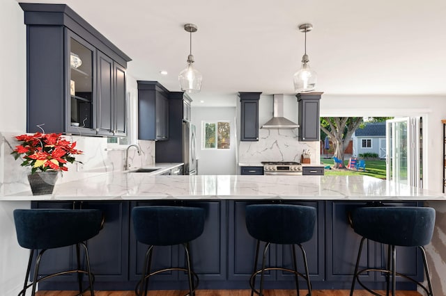 kitchen with a breakfast bar, pendant lighting, and wall chimney exhaust hood