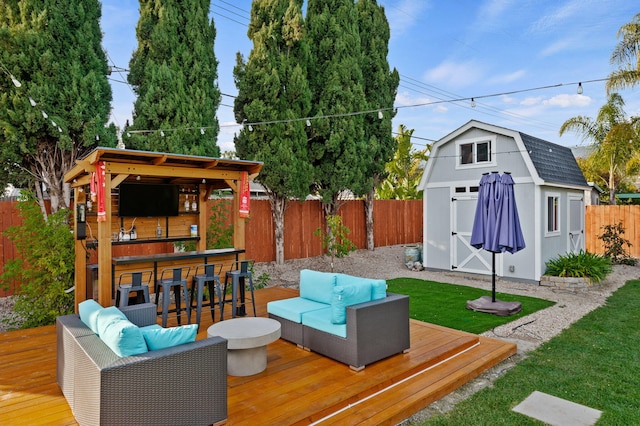 wooden deck with a storage shed, exterior bar, an outdoor hangout area, and a yard