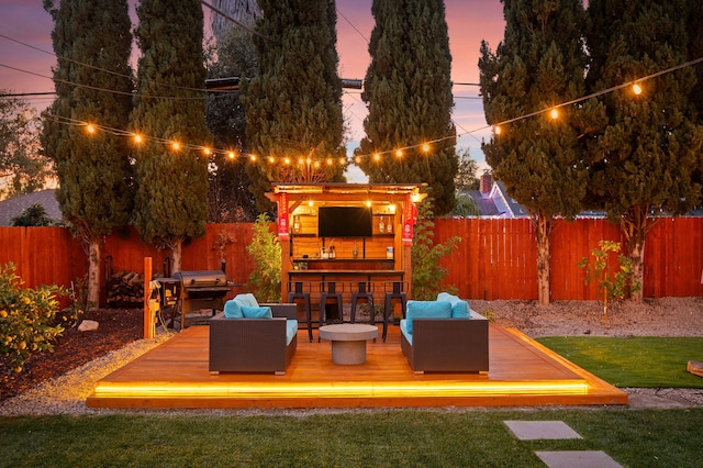 patio terrace at dusk featuring an outdoor hangout area, exterior bar, and a deck