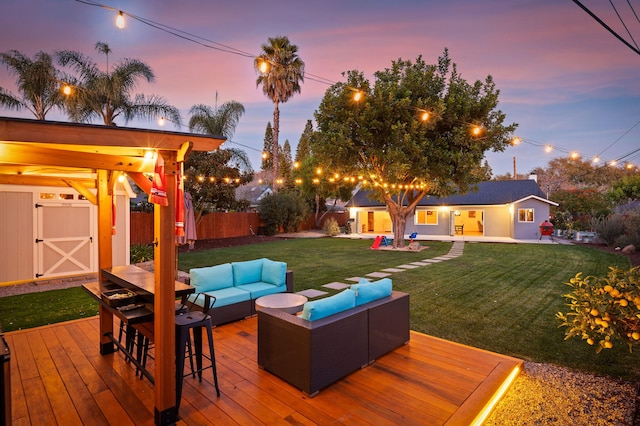 deck at dusk with a shed, outdoor lounge area, and a lawn