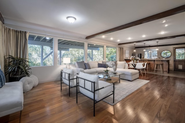 living room featuring ornamental molding, beam ceiling, baseboards, and wood finished floors