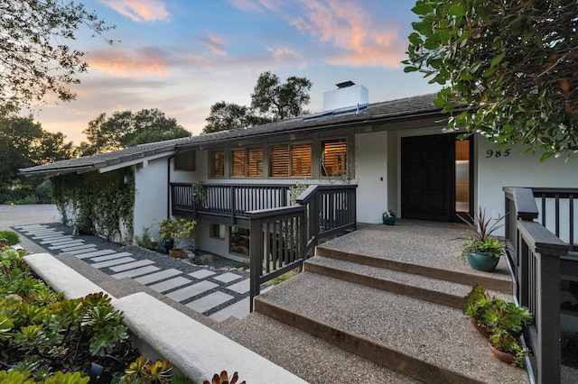 exterior space featuring roof with shingles, a porch, and stucco siding