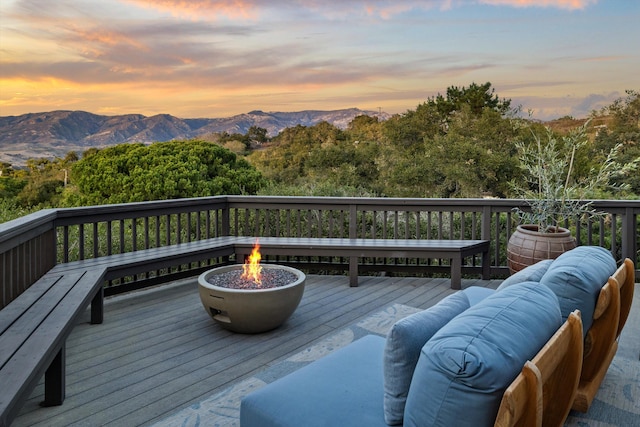 deck at dusk with an outdoor living space with a fire pit and a mountain view