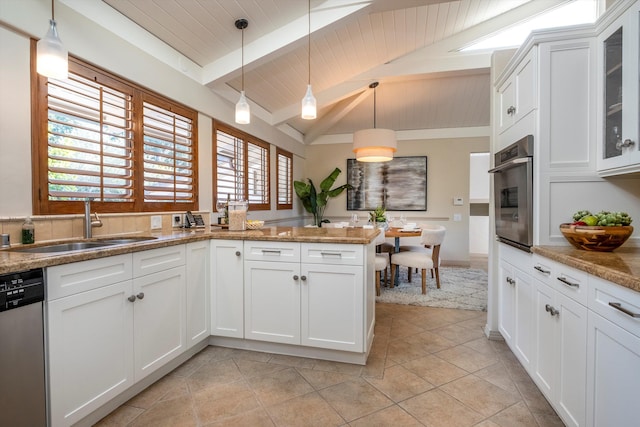 kitchen with lofted ceiling with beams, appliances with stainless steel finishes, a peninsula, white cabinetry, and a sink