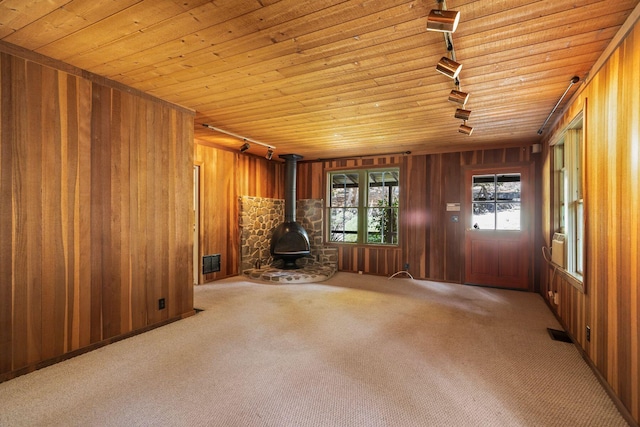 interior space with wooden ceiling, a wood stove, light carpet, and track lighting