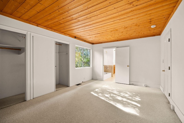 unfurnished bedroom with light carpet, ensuite bathroom, and wooden ceiling