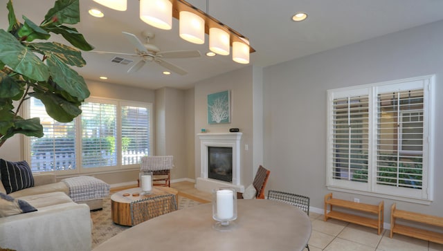 living room featuring light tile patterned floors, visible vents, baseboards, a glass covered fireplace, and recessed lighting