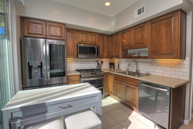 kitchen featuring light stone countertops, sink, tasteful backsplash, light tile patterned floors, and appliances with stainless steel finishes