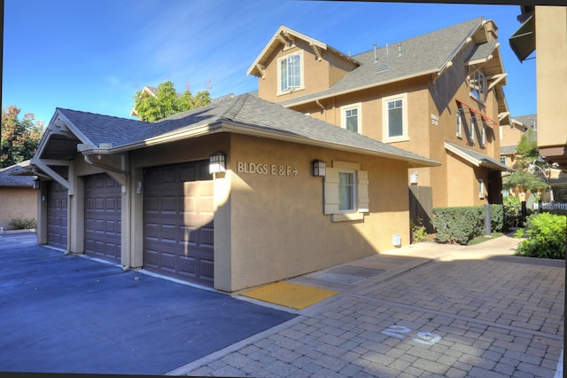 view of side of property featuring a shingled roof and stucco siding