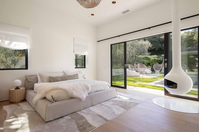 bedroom with access to outside, light wood-type flooring, and multiple windows