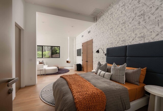 bedroom with light wood-type flooring and a towering ceiling