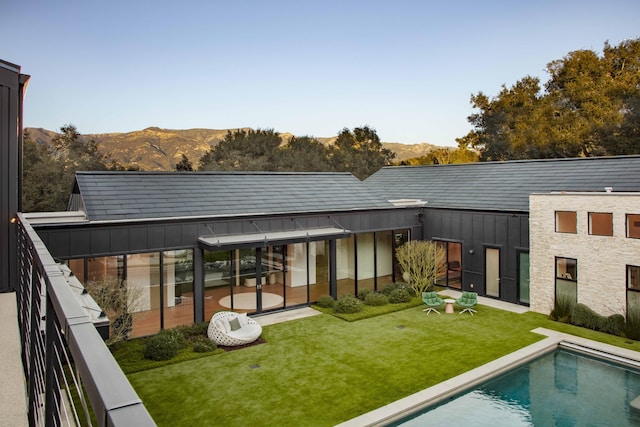 back of house with a mountain view and a lawn