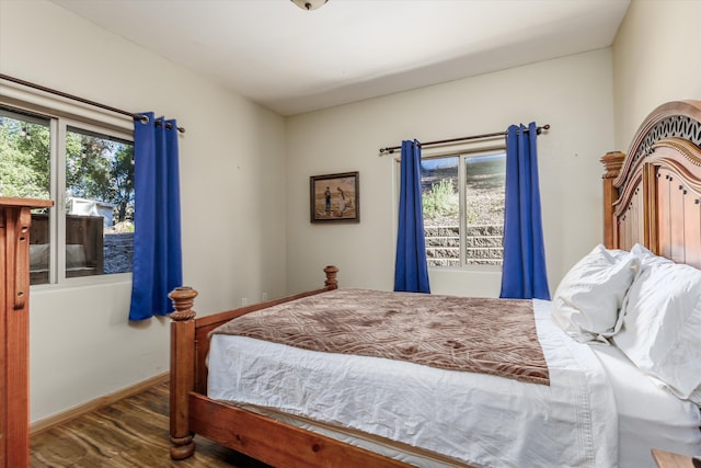 bedroom with multiple windows and dark hardwood / wood-style flooring