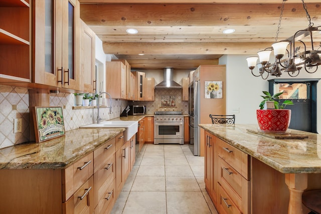 kitchen with appliances with stainless steel finishes, light stone counters, wall chimney exhaust hood, sink, and decorative light fixtures