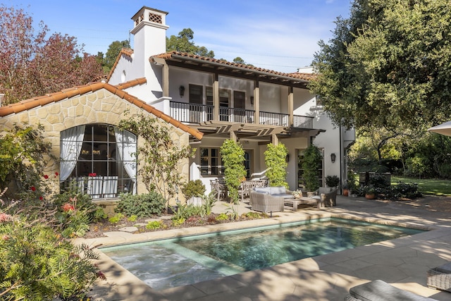 rear view of house featuring a patio area, an outdoor living space, and a balcony