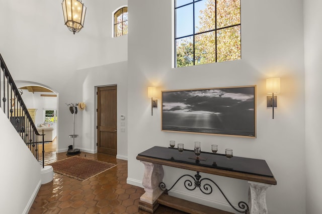 tiled entrance foyer with a high ceiling and a wealth of natural light