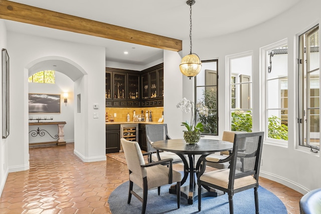 dining area featuring light tile patterned floors, indoor bar, wine cooler, and beam ceiling