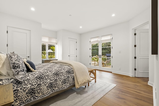 bedroom with hardwood / wood-style floors, access to outside, and multiple windows