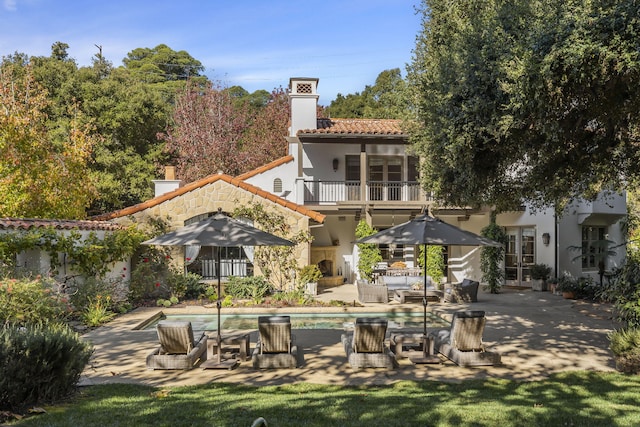 rear view of house with an outdoor living space, a patio area, and a balcony