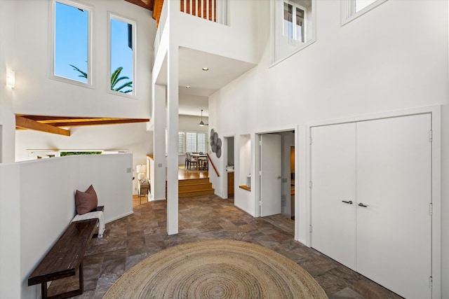 foyer with beamed ceiling and a towering ceiling