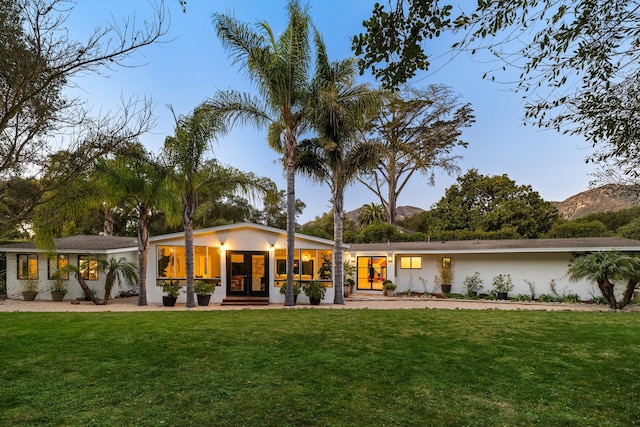 rear view of house with french doors, a yard, and a mountain view