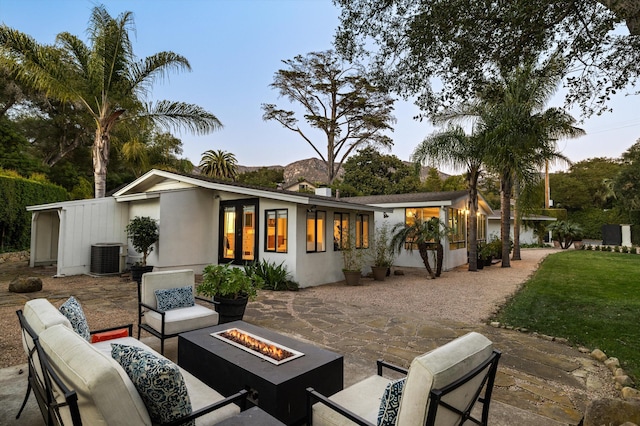 back of house with an outdoor living space with a fire pit, a patio, and central AC