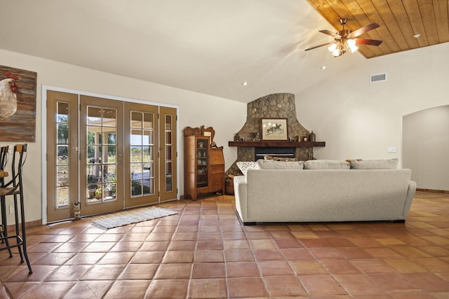 living room featuring ceiling fan, french doors, wooden ceiling, a stone fireplace, and vaulted ceiling