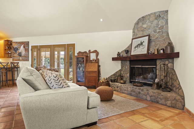 living room with a stone fireplace, french doors, and vaulted ceiling