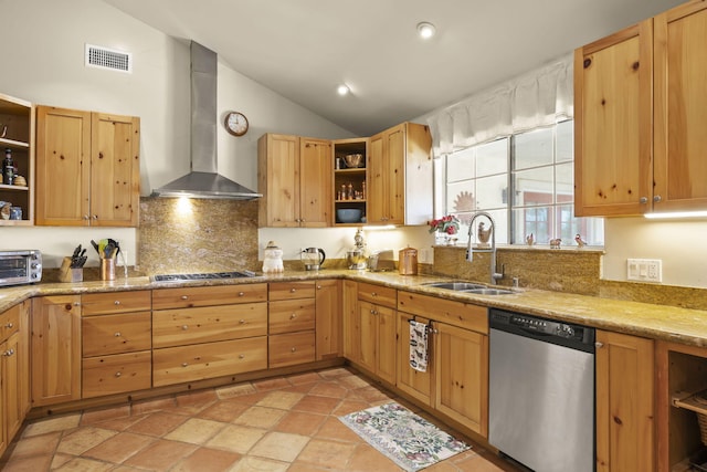 kitchen with sink, stainless steel appliances, wall chimney range hood, light stone counters, and vaulted ceiling