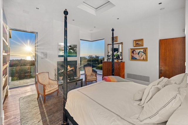 bedroom with a fireplace, hardwood / wood-style flooring, and multiple windows