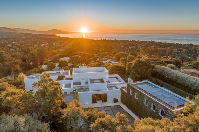 aerial view at dusk featuring a water view