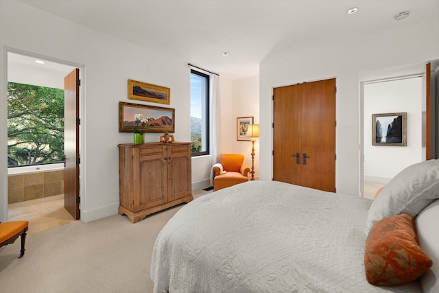 bedroom with connected bathroom, multiple windows, and light carpet