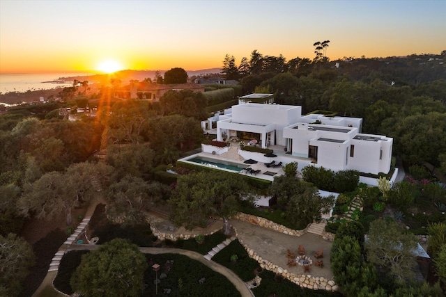 aerial view at dusk featuring a water view