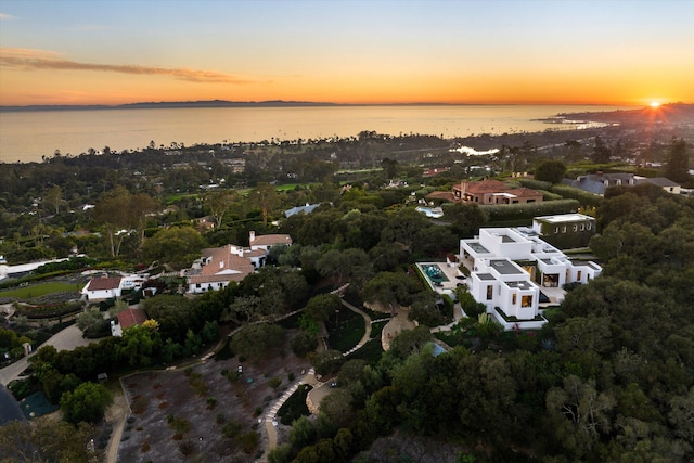 aerial view at dusk featuring a water view