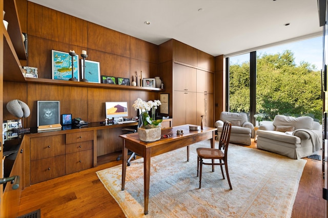 home office featuring wooden walls, light hardwood / wood-style flooring, and expansive windows