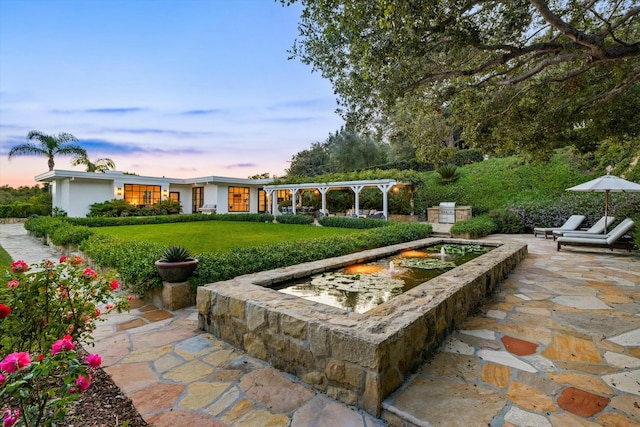 patio terrace at dusk with a lawn and a pergola