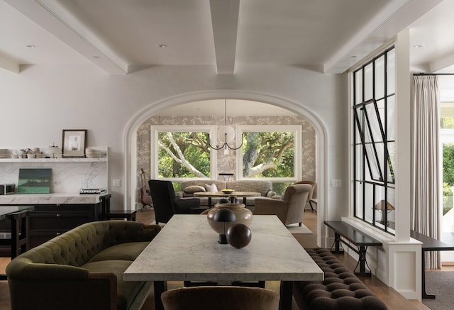 dining room featuring beamed ceiling, wood-type flooring, and an inviting chandelier