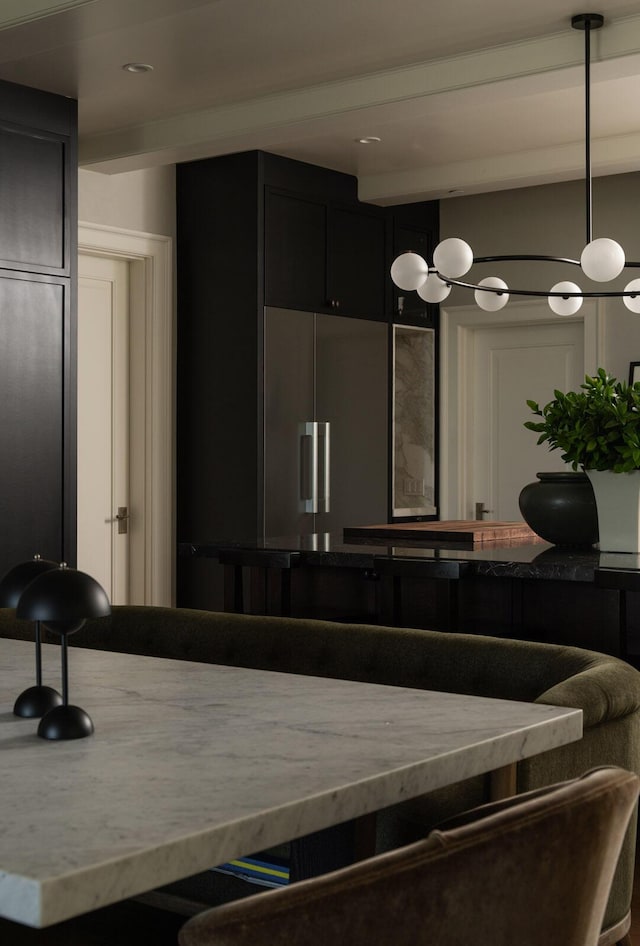 kitchen with beamed ceiling, paneled refrigerator, and decorative light fixtures