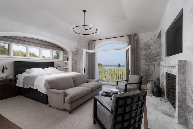 bedroom with a premium fireplace, lofted ceiling, an inviting chandelier, and a tray ceiling