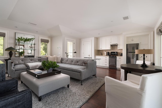 living room featuring lofted ceiling, plenty of natural light, and dark hardwood / wood-style floors