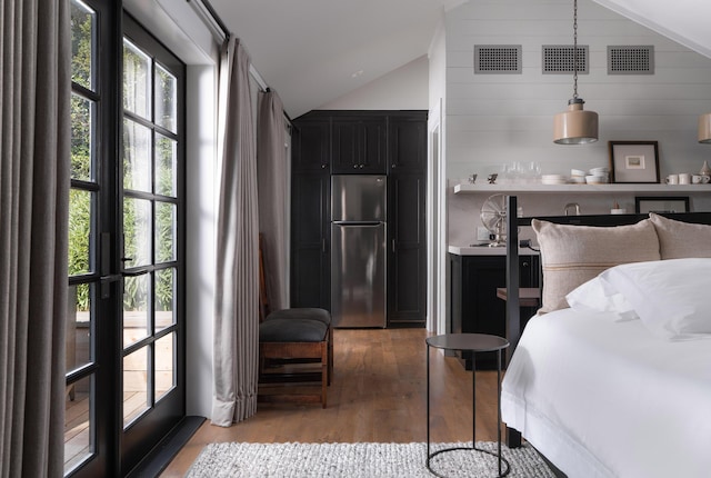 bedroom featuring hardwood / wood-style flooring, lofted ceiling, and stainless steel fridge