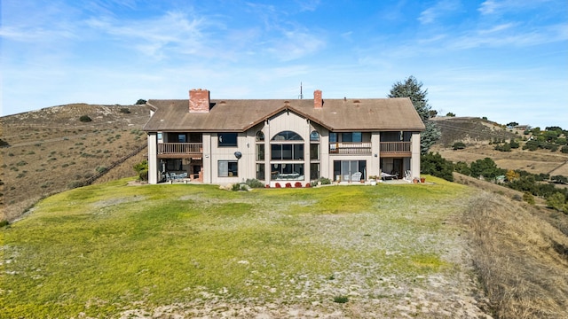 back of property featuring a balcony and a yard