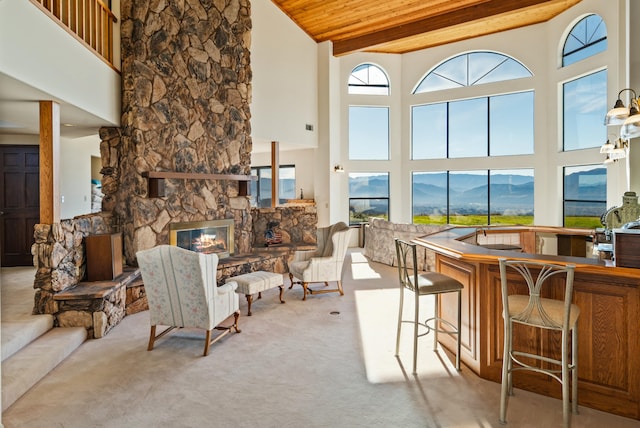 carpeted living room featuring a mountain view, wooden ceiling, a towering ceiling, a fireplace, and a wealth of natural light