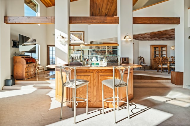 kitchen featuring kitchen peninsula, a breakfast bar, high vaulted ceiling, and light colored carpet