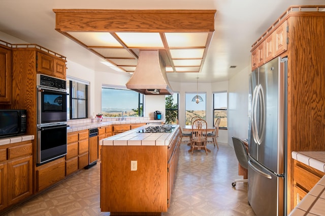 kitchen featuring a center island, sink, stainless steel appliances, tile countertops, and custom range hood