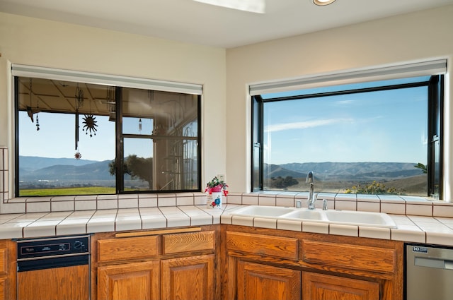 kitchen with tile countertops, a mountain view, sink, and stainless steel dishwasher